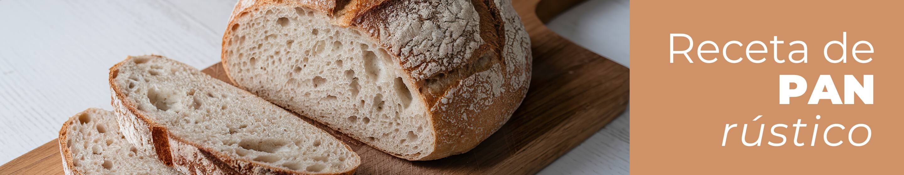Hogaza de pan rústico casero horneado con ingredientes Dia, colocada sobre una mesa de madera de cocina con un paño de tela, cortada en cuatro rebanadas grandes donde se aprecia la miga esponjosa y la corteza crujiente.